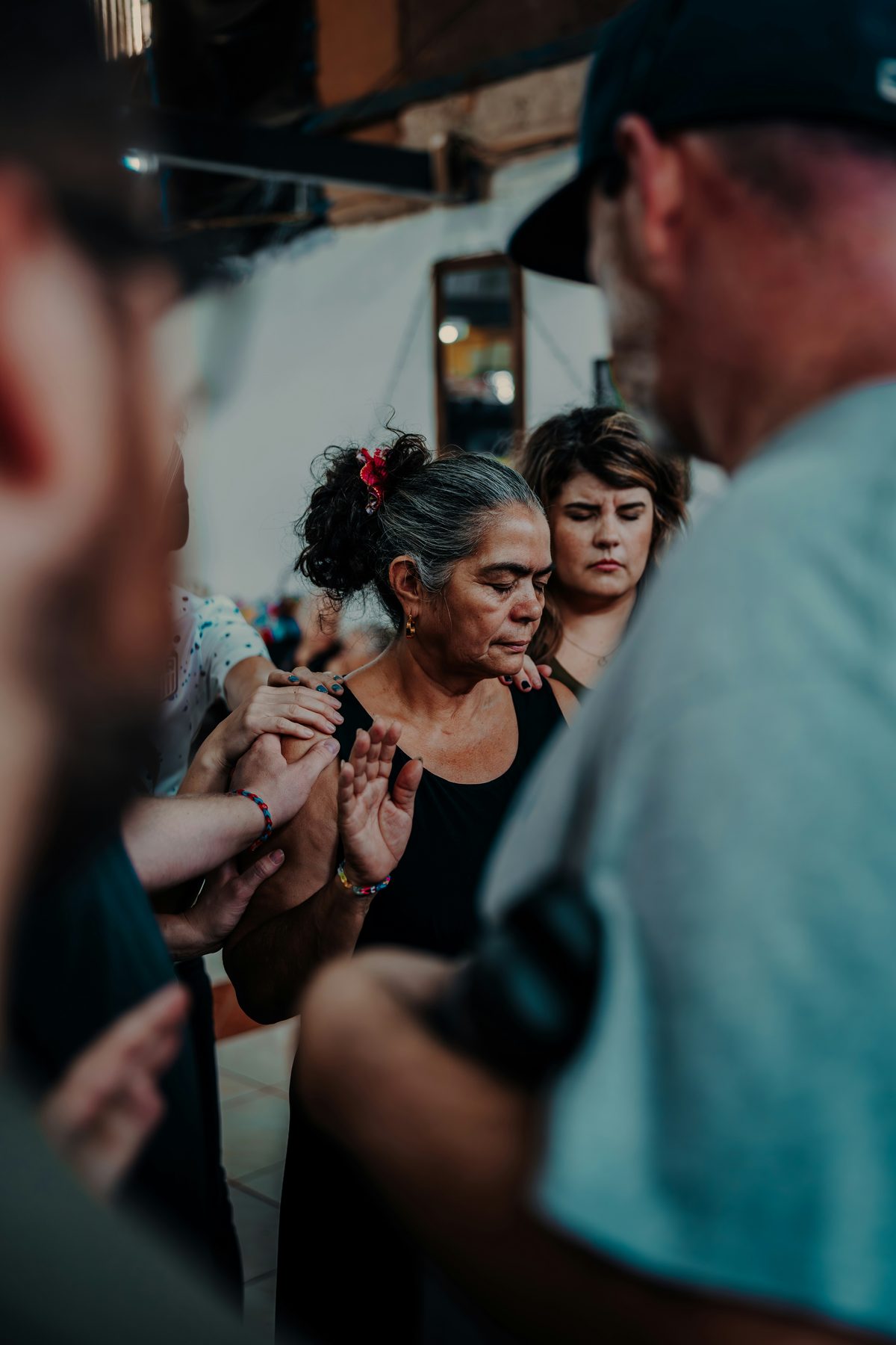 Volunteers from Hands of God Serving laying hands and praying over a woman during a community outreach gathering.