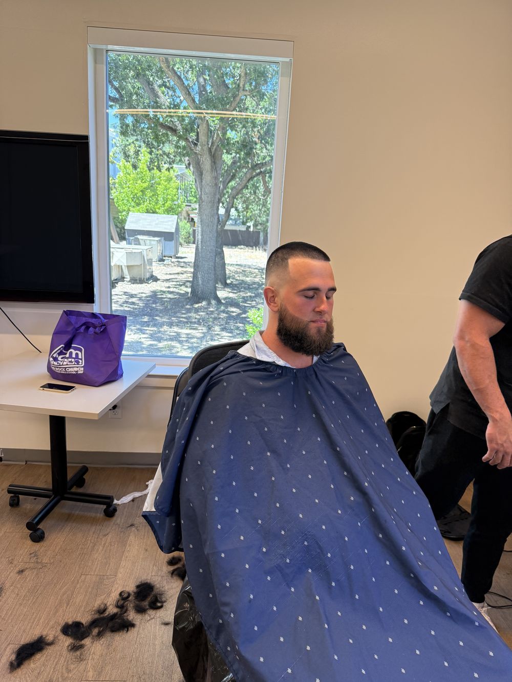 A man receiving a clean fresh cut by the window during the community haircut event.