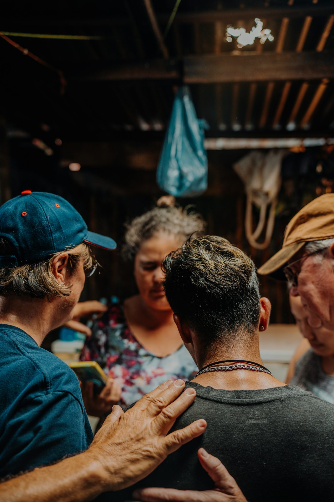 Volunteers laying hands and praying over a person during a Hands of God Serving outreach gathering.